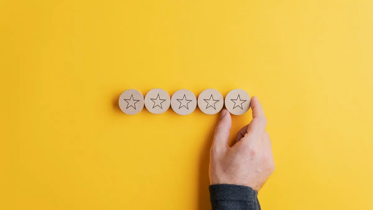 5 stars on a yellow background. The last star is placed by a hand.